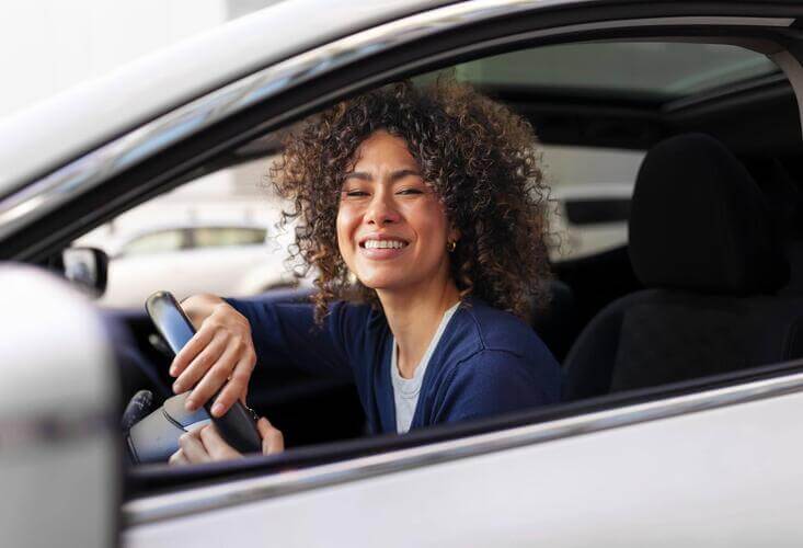 Mulher no volante sorrindo para a câmera