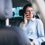 Mulher sorrindo e falando ao celular no banco traseiro de um carro.